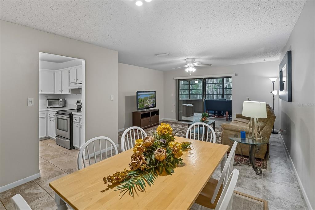 A dining area with a wooden table opens into a living room and kitchen — 2746 SW 14 DRIVE UNIT 2746, GAINESVILLE, FL