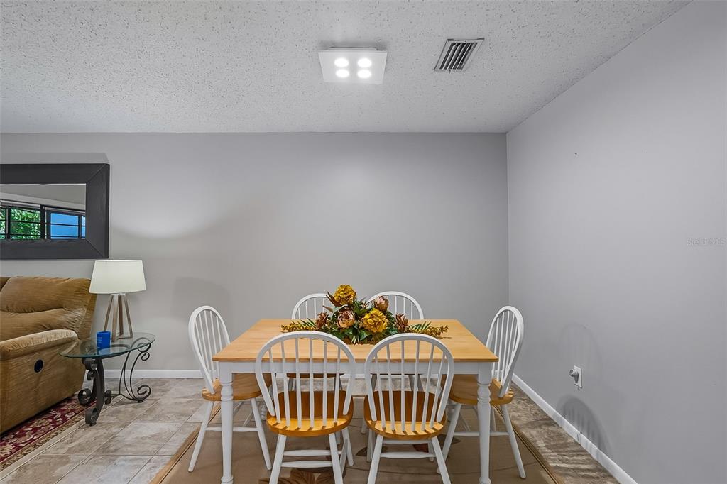 A dining area features a light wood table with four white chairs and tile flooring — 2746 SW 14 DRIVE UNIT 2746, GAINESVILLE, FL
