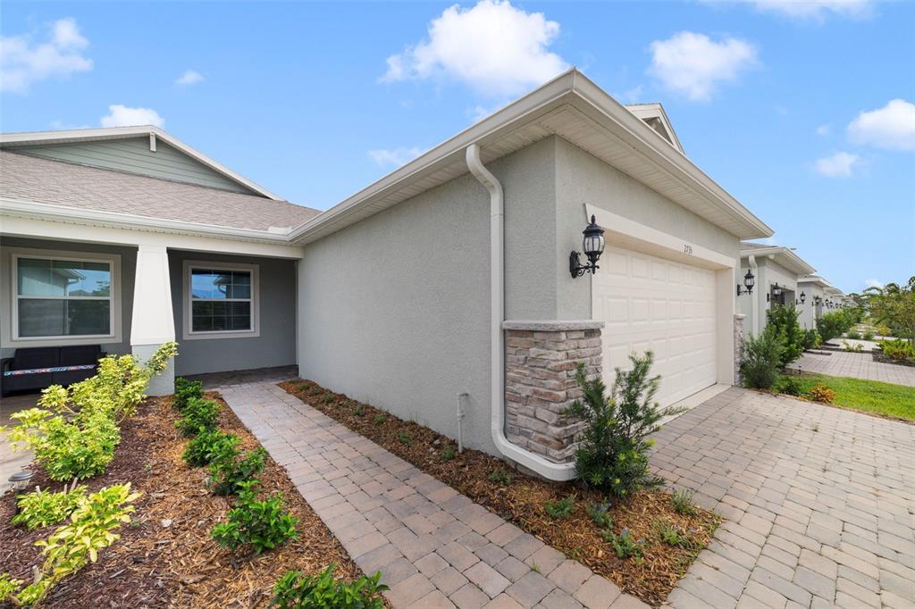 A single-story house exterior features a paved walkway, a garage, and a small front garden — 2735 SUMMER RETREAT LANE, KISSIMMEE, FL