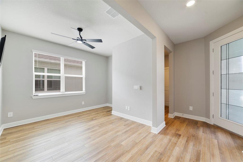 An empty room with light gray walls, wood-look flooring, a ceiling fan, and glass-paneled door — 2735 SUMMER RETREAT LANE, KISSIMMEE, FL