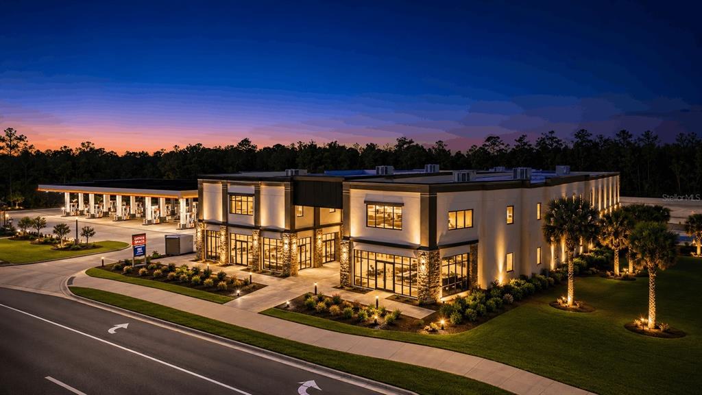 An exterior view of a modern commercial building with an adjacent gas station at dusk — 4560 W IRLO BRONSON MEMORIAL HIGHWAY UNIT 203, KISSIMMEE, FL