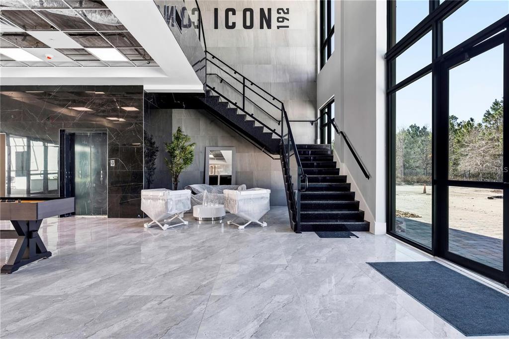 A modern lobby features marble floors, a black staircase, and floor-to-ceiling windows — 4560 W IRLO BRONSON MEMORIAL HIGHWAY UNIT 203, KISSIMMEE, FL