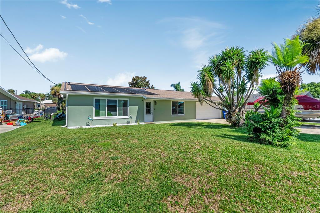 A single-story house with green siding, a solar-paneled roof, and a front lawn — 988 SHOCKNEY DRIVE, ORMOND BEACH, FL