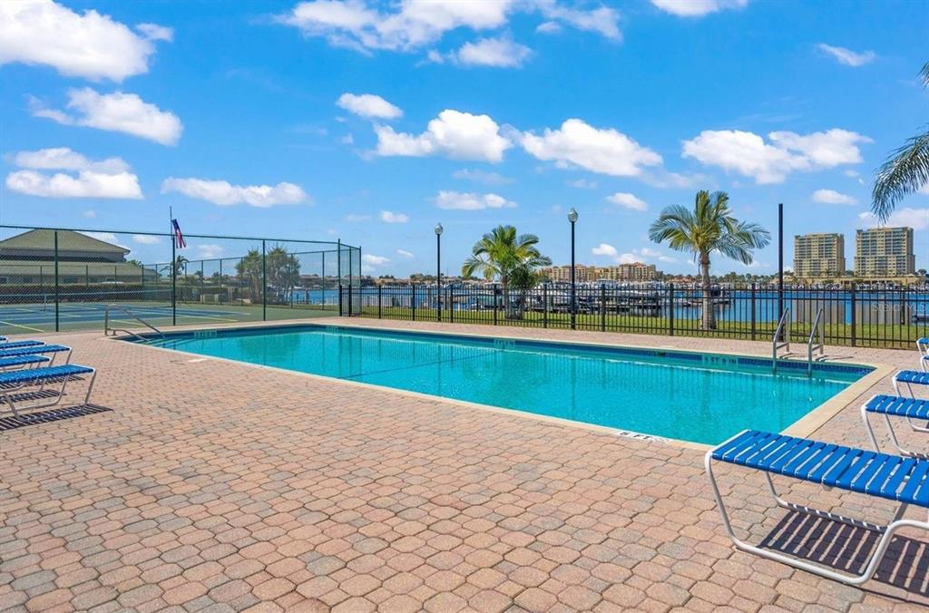 A rectangular swimming pool sits on a brick patio next to a fenced tennis court — 312 11TH AVENUE E, PALMETTO, FL