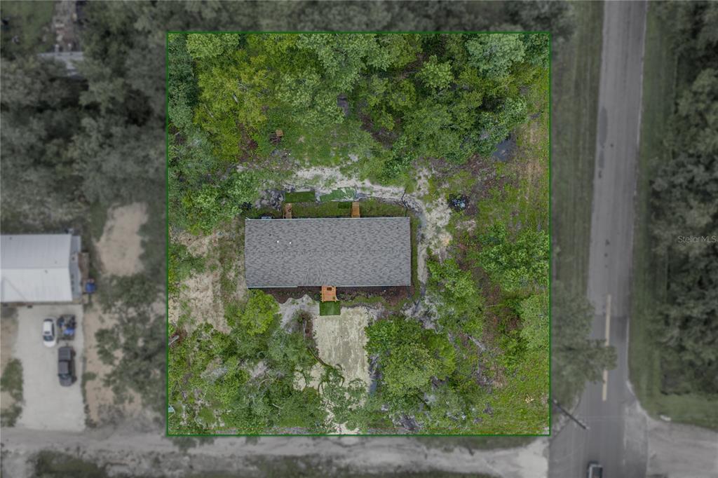 An aerial view shows a rectangular house situated on a wooded lot near a road — 11957 SW 35TH STREET, WEBSTER, FL