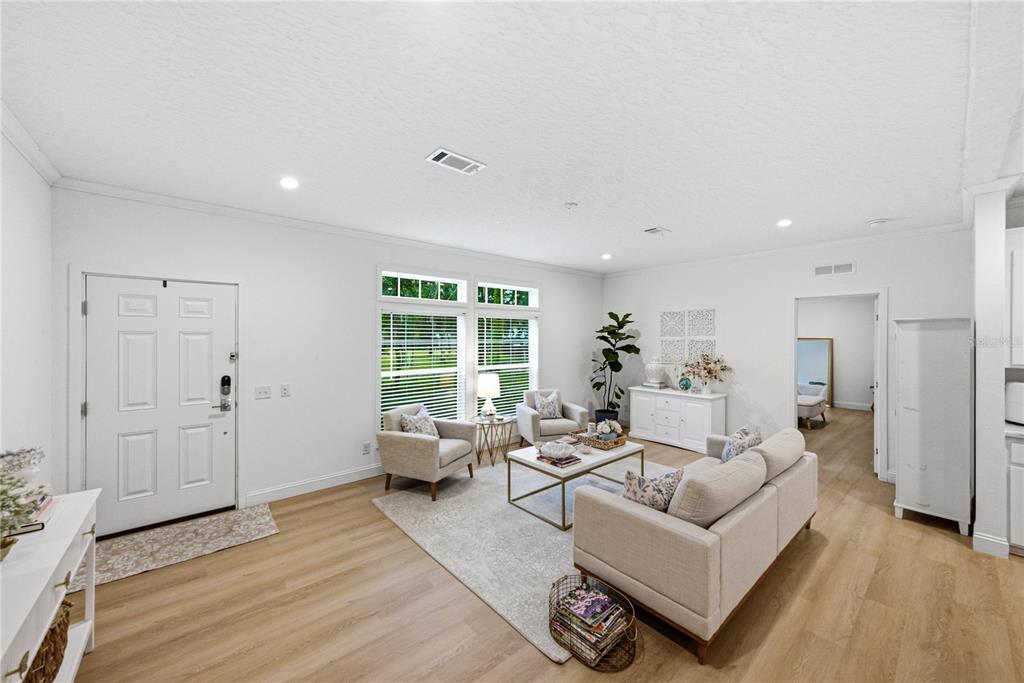 A bright living room features light wood flooring, white walls, and a neutral furniture arrangement — 11957 SW 35TH STREET, WEBSTER, FL