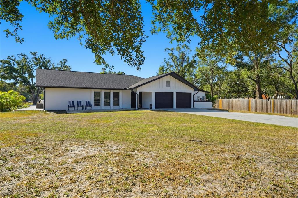 A single-story white house with a dark roof and a three-car garage — 6370 90TH AVENUE N, PINELLAS PARK, FL