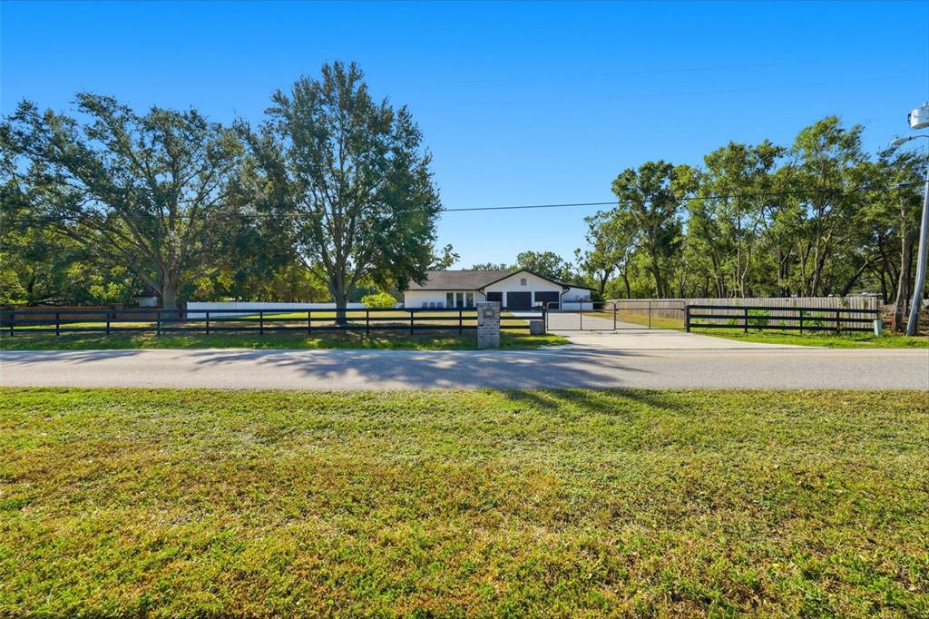 A white house with a dark roof sits behind a black fence and gate — 6370 90TH AVENUE N, PINELLAS PARK, FL