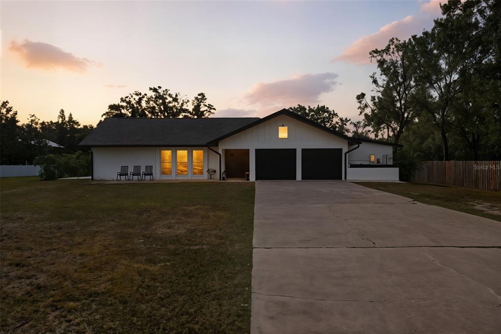 A white single-story house with a two-car garage and a concrete driveway at sunset — 6370 90TH AVENUE N, PINELLAS PARK, FL