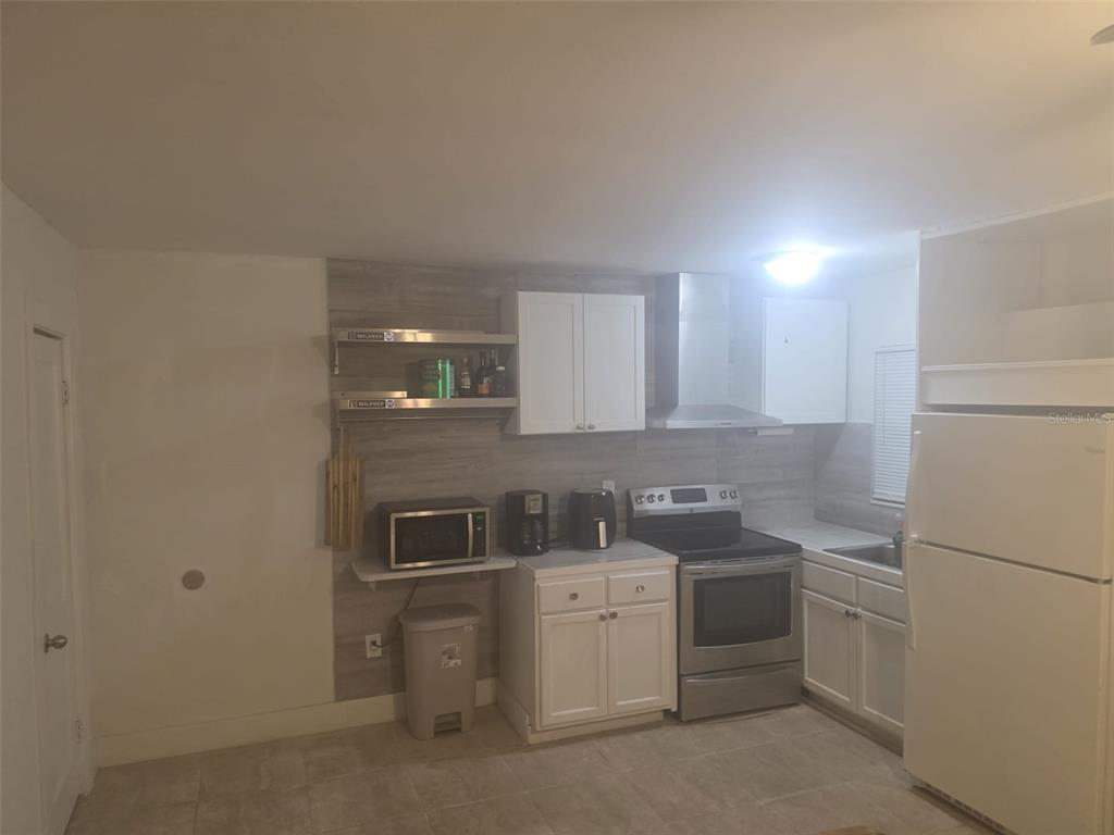 A kitchen features white cabinets, stainless steel appliances, and wood-look wall paneling — 1844 JOHN RIVERS STREET UNIT S, SARASOTA, FL