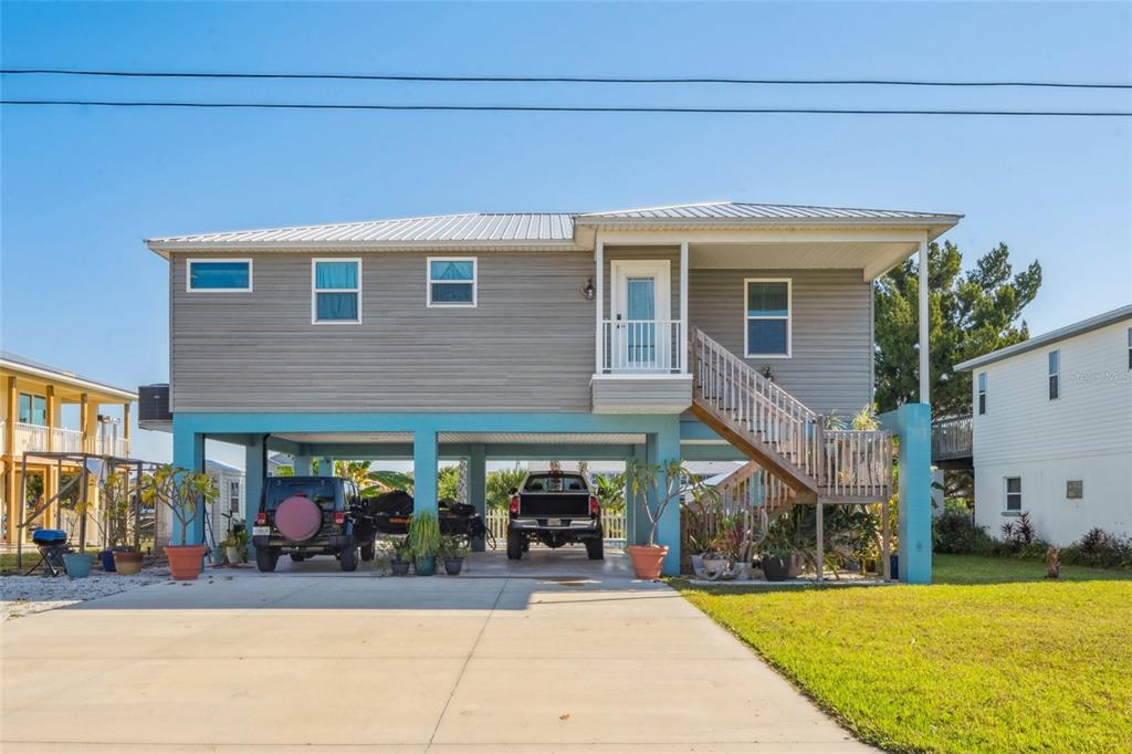 A stilt house with gray siding, a concrete driveway, and a wooden staircase to the entrance — 3270 HIBISCUS DRIVE, HERNANDO BEACH, FL
