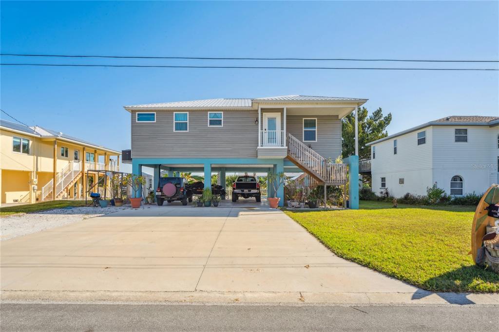 A stilt house with gray siding, a concrete driveway, and a covered ground-level parking area — 3270 HIBISCUS DRIVE, HERNANDO BEACH, FL