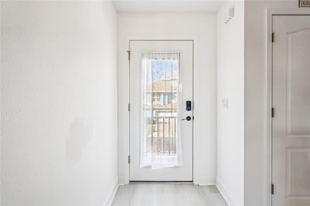 A white entryway features a door with a glass insert, sheer curtain, and light flooring — 3270 HIBISCUS DRIVE, HERNANDO BEACH, FL