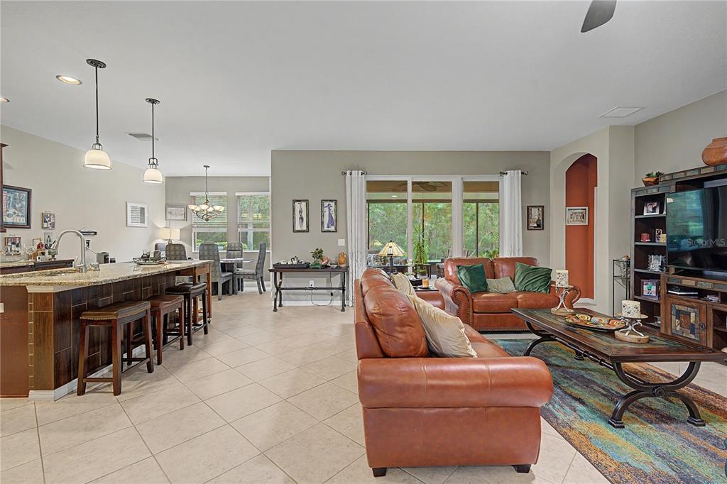 An open-concept living room and kitchen feature tile floors, leather furniture, and a dining area — 29358 GRASS BUNKER DRIVE, SAN ANTONIO, FL