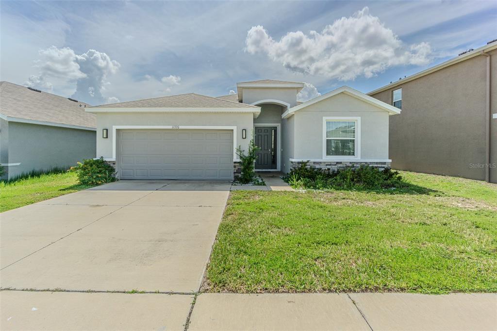 An open-concept kitchen and living area features tile flooring, white cabinetry, and sliding glass doors — 11370 TIMBER GROVE LANE, BROOKSVILLE, FL