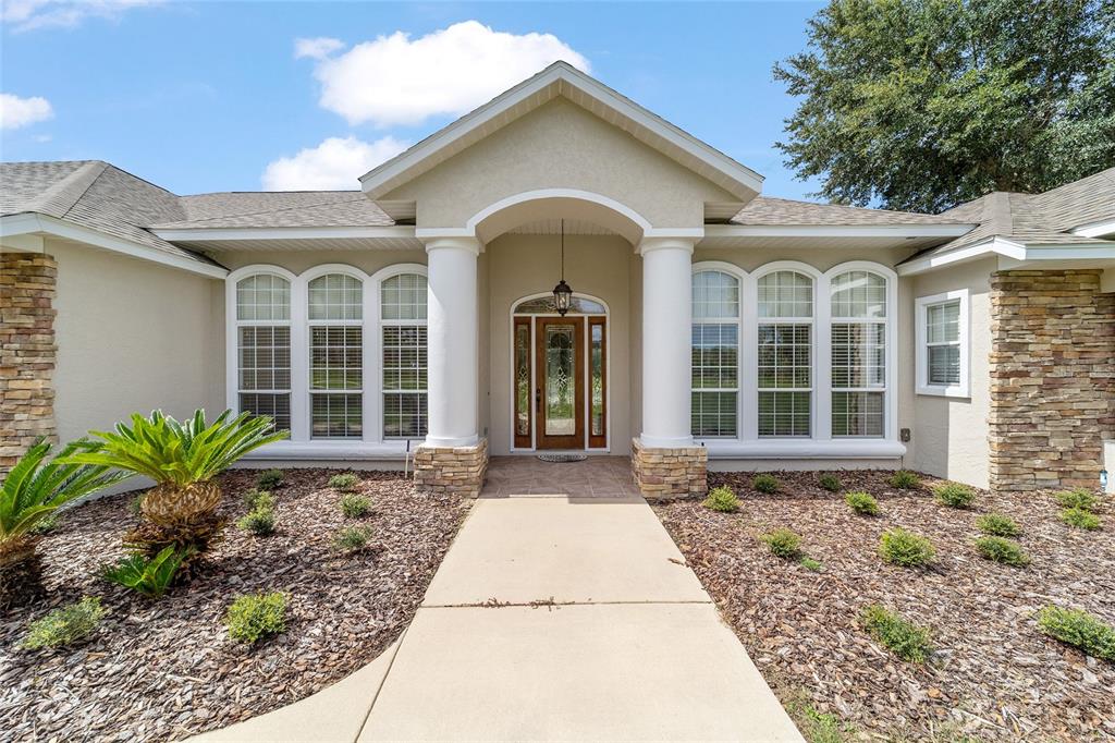 The exterior of a house features a stone-accented facade, white columns, and a central entryway — 8280 SE 15TH COURT, OCALA, FL
