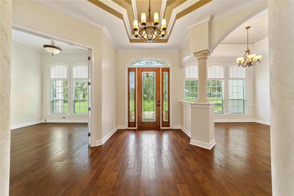 A foyer with hardwood floors, a tray ceiling, and a wooden front door with glass panels — 8280 SE 15TH COURT, OCALA, FL