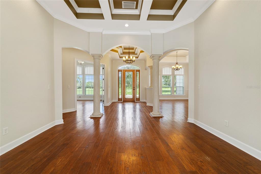 An entryway with hardwood floors, two columns, and a coffered ceiling leading to a front door — 8280 SE 15TH COURT, OCALA, FL