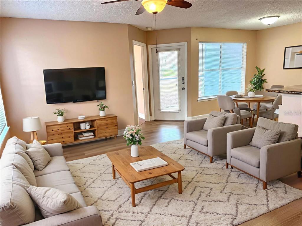 A covered patio features a wooden loveseat, a matching coffee table, and two potted plants — 731 SUGAR BAY WAY UNIT 103, LAKE MARY, FL