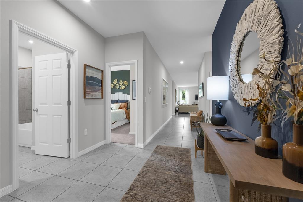 A hallway with light gray tile floors leads past a bedroom and bathroom toward a living area — 1413 CHAMBORD DRIVE, EAGLE LAKE, FL