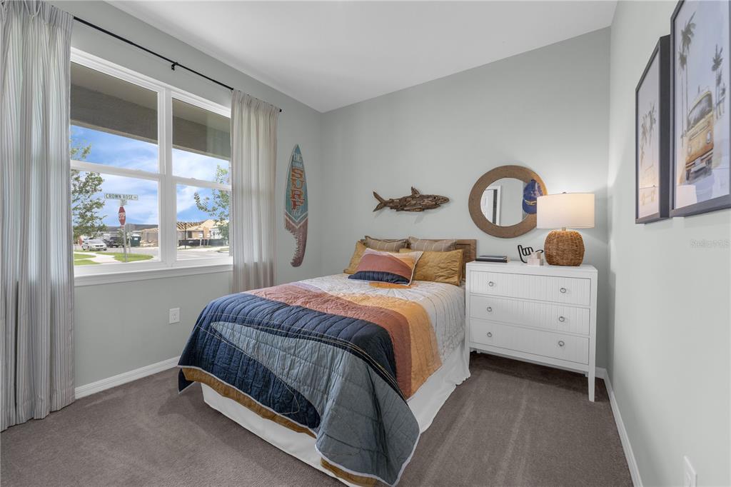 A bedroom features a bed with a surf-themed quilt, a white dresser, and a window — 1413 CHAMBORD DRIVE, EAGLE LAKE, FL