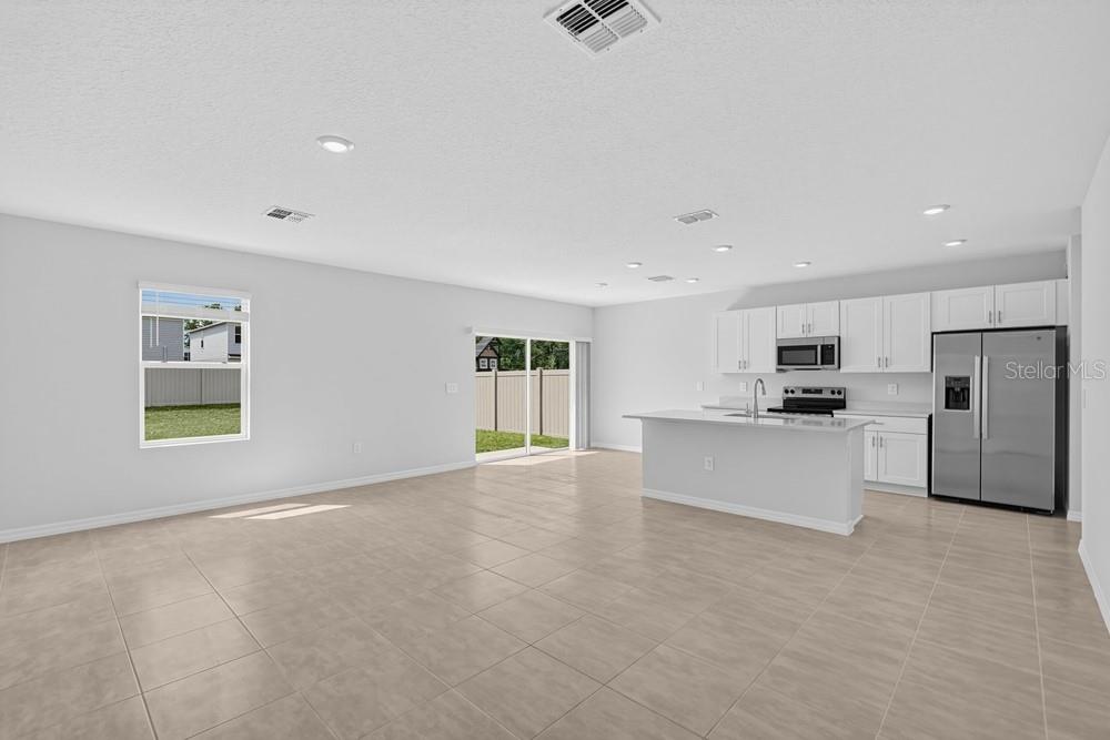 An open-concept living room and kitchen featuring a large sectional sofa and kitchen island — 12422 WHISK COURT, HUDSON, FL