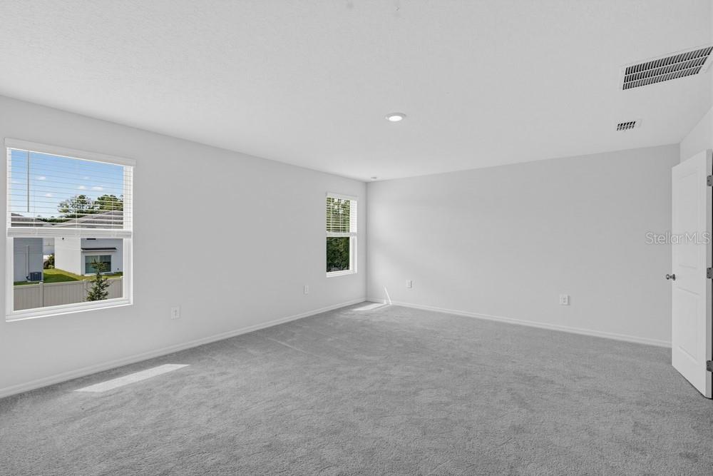 An open-concept kitchen with granite countertops and a large island overlooks a living area — 12422 WHISK COURT, HUDSON, FL