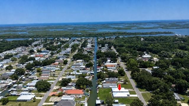 A waterfront house with a screened deck and private dock sits along a green canal — 124 INDIAN CREEK ROAD, OAK HILL, FL