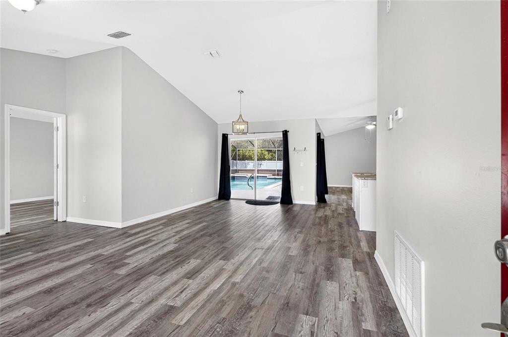 A modern kitchen features white cabinets, granite countertops, stainless steel appliances, and wood-look flooring — 718 TOULON DRIVE, KISSIMMEE, FL
