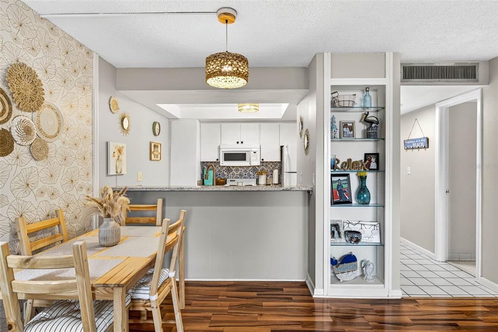 A kitchen features white cabinets, a white microwave, a white stove, and blue patterned backsplash — 2614 COVE CAY DRIVE UNIT 405, CLEARWATER, FL