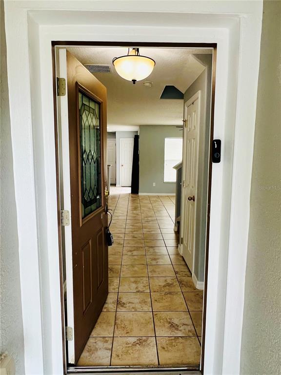 An open front door reveals a tiled entryway leading into a home interior — 13672 CYGNUS DRIVE, ORLANDO, FL