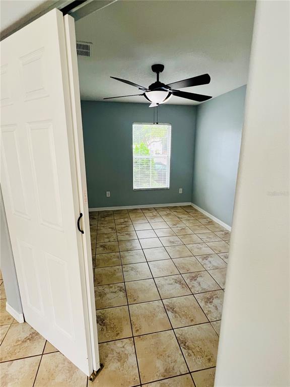 A bedroom with light blue walls, a ceiling fan, and tan tile flooring — 13672 CYGNUS DRIVE, ORLANDO, FL