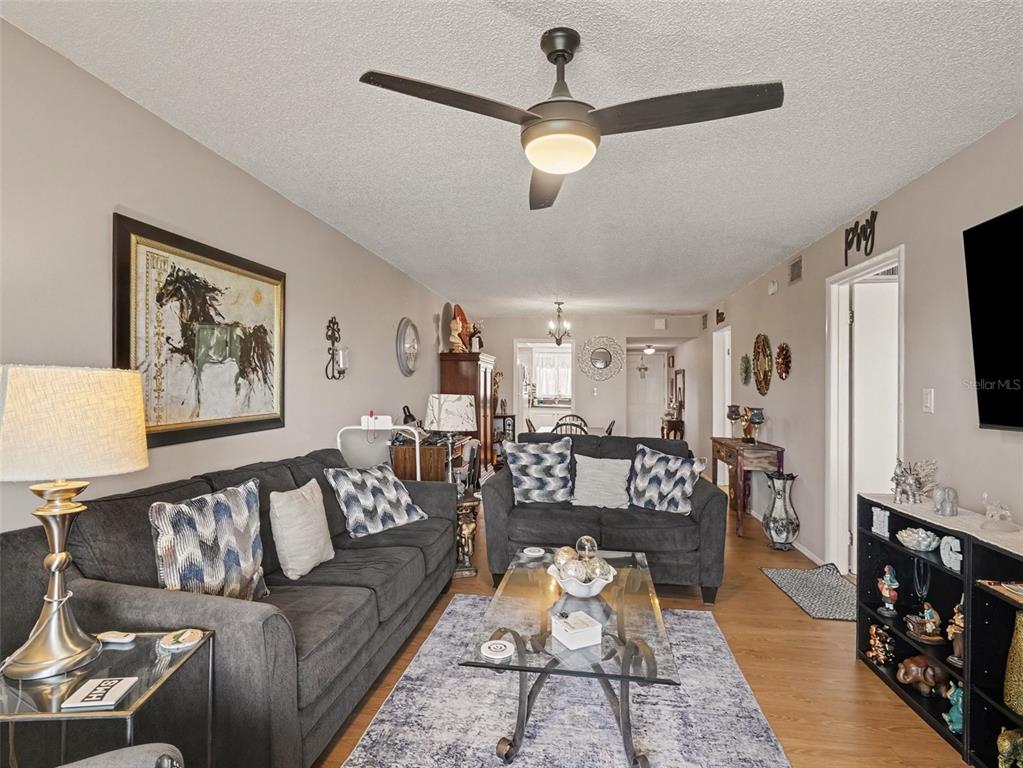 A living room features two dark sofas, a glass coffee table, and a ceiling fan — 4171 HERON WAY UNIT E309, BRADENTON, FL