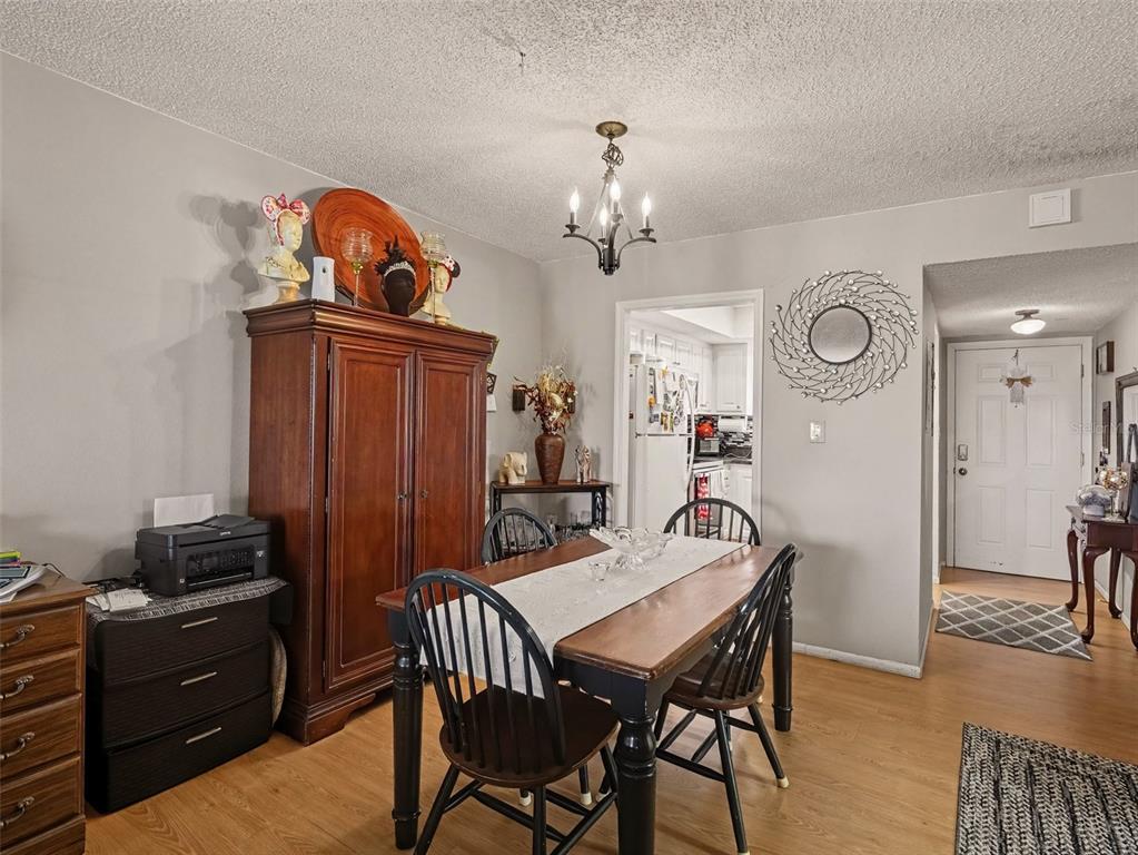 A dining room features a wooden table with chairs, a large armoire, and light flooring — 4171 HERON WAY UNIT E309, BRADENTON, FL