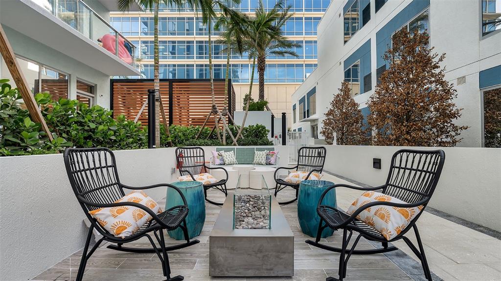 An outdoor patio features four black rocking chairs, a fire pit, and blue accent tables — 225 1ST AVENUE N UNIT A2, ST PETERSBURG, FL