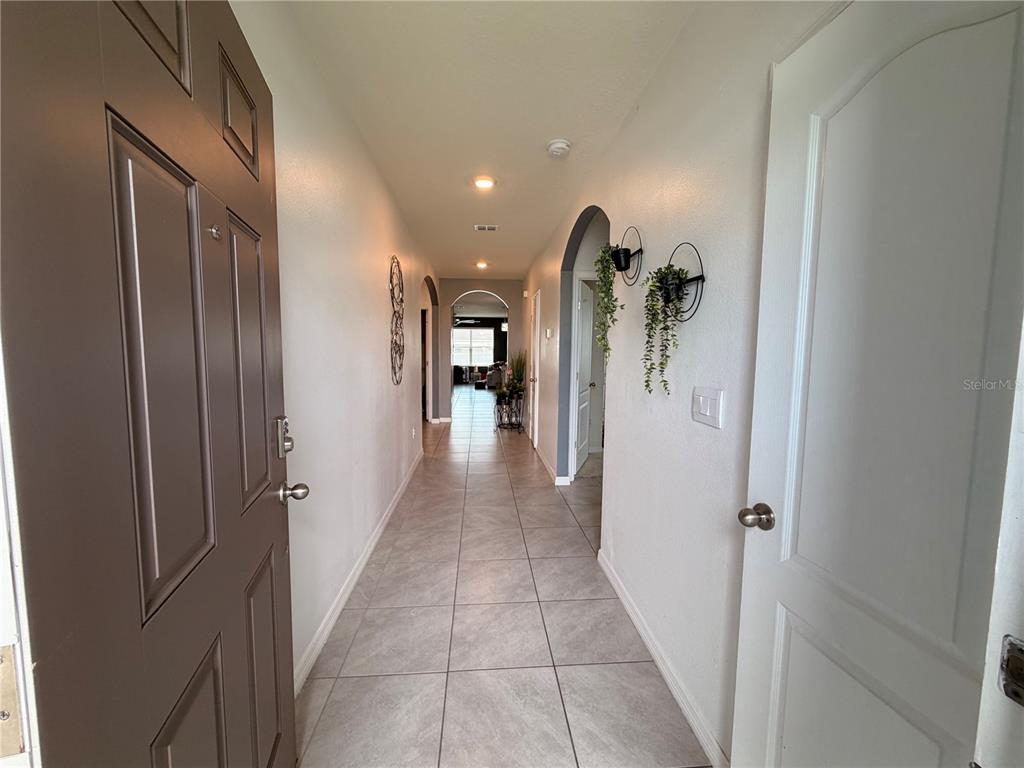 A tiled entryway hallway leads toward a living area with arched doorways and wall decor — 233 TIFFANY COURT, KISSIMMEE, FL