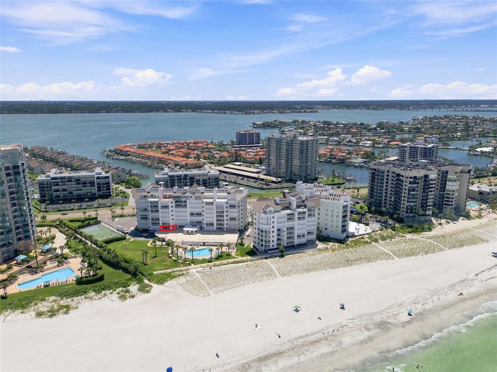 An aerial view shows several beachfront condominium buildings along a sandy coastline — 1582 GULF BOULEVARD UNIT 1106, CLEARWATER, FL