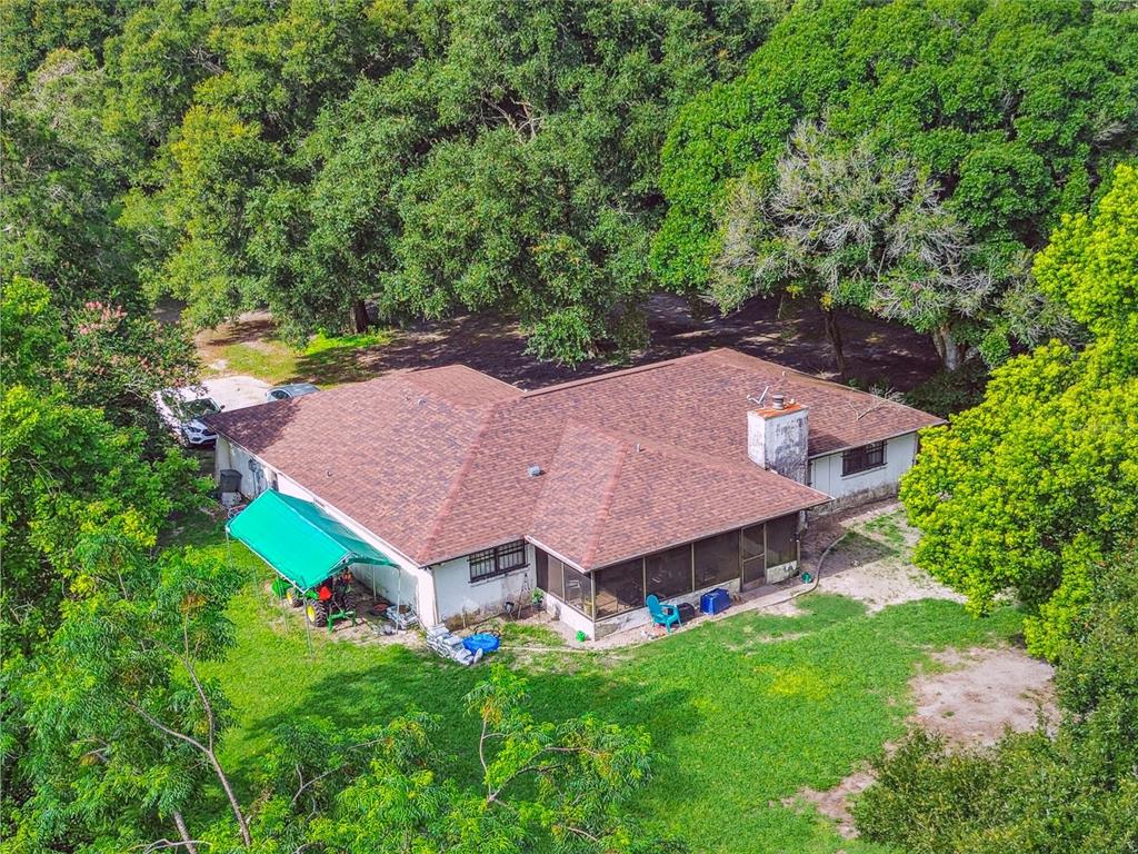 An aerial view of a single-story house with a brown roof, chimney, and screened porch — 18139 BENES ROUSH ROAD, BROOKSVILLE, FL