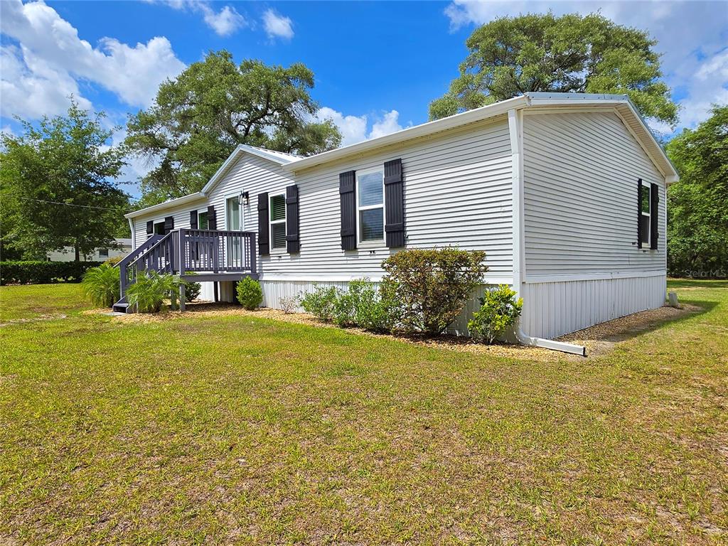A single-story manufactured home with light siding and a small wooden deck — 6398 S TROPICANA AVENUE, LECANTO, FL