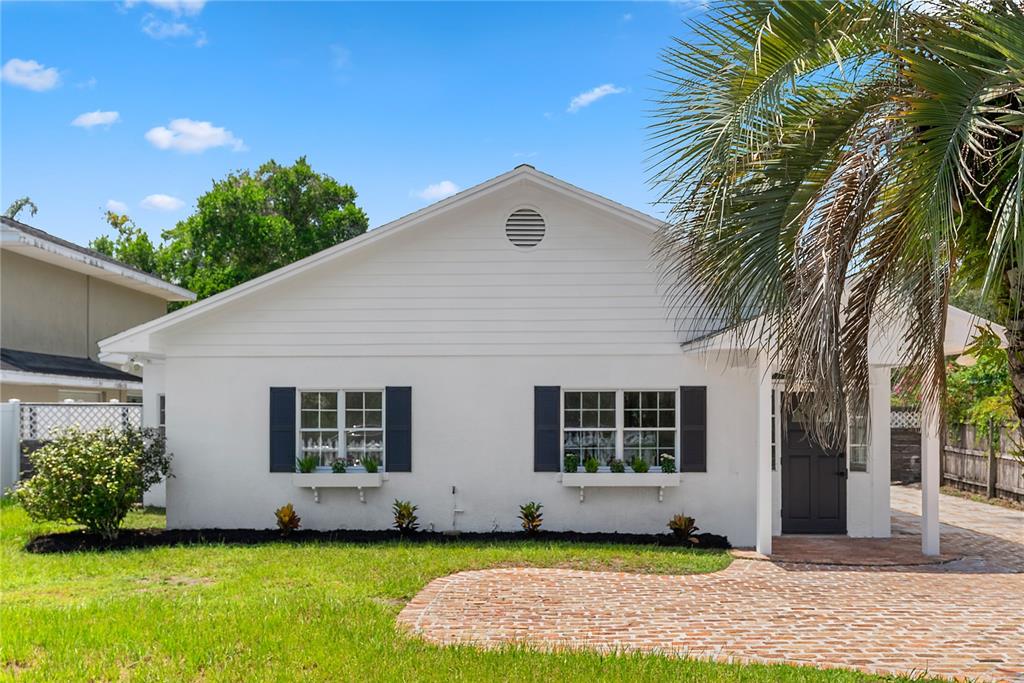A white single-story house with dark shutters, window boxes, and a brick driveway — 1313 S DENNING DRIVE, WINTER PARK, FL