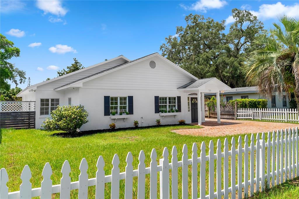 A white single-story house features a brick driveway, a white picket fence, and dark shutters — 1313 S DENNING DRIVE, WINTER PARK, FL