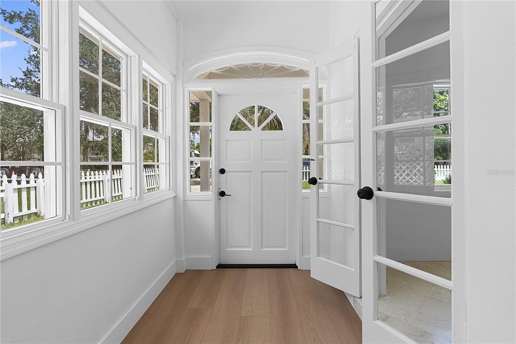 A bright entryway features a white front door, glass-paned side doors, and light wood flooring — 1313 S DENNING DRIVE, WINTER PARK, FL