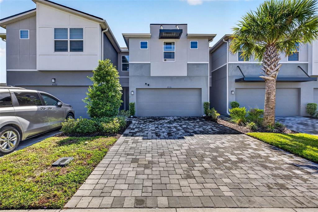 A paved driveway leads to the garage of a modern two-story townhouse with gray siding — 4116 CLOUD HOPPER WAY, LUTZ, FL