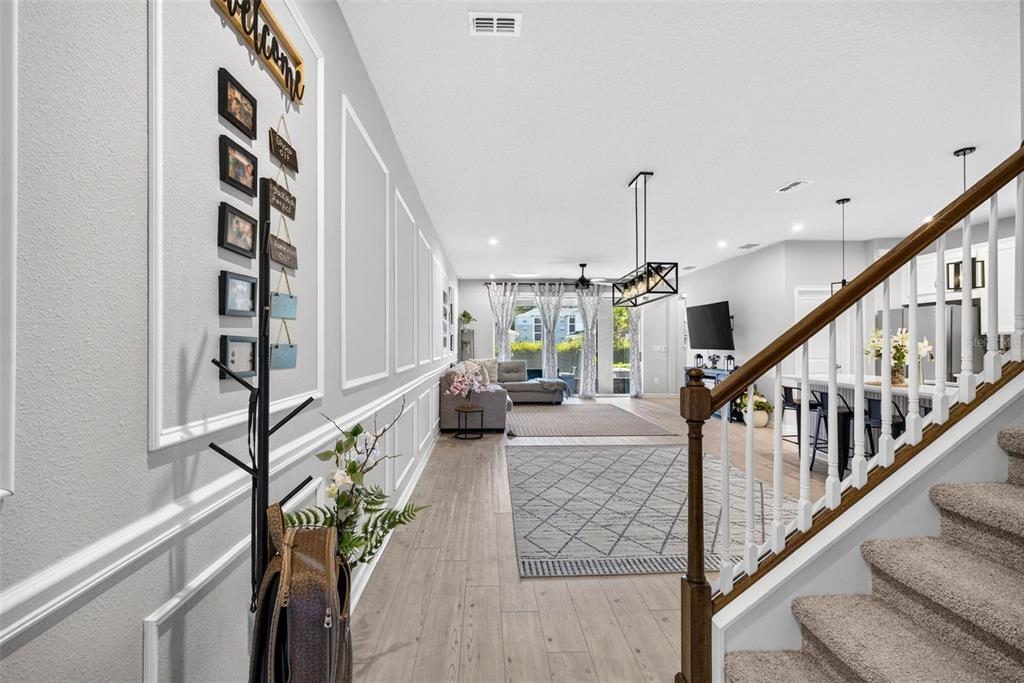 A view from a staircase looking down a hallway toward an open-concept living area — 4116 CLOUD HOPPER WAY, LUTZ, FL