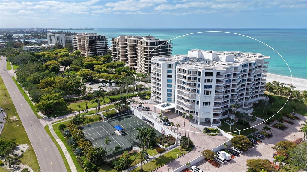 An aerial view shows a white multi-story condominium building located next to a sandy beach — 455 LONGBOAT CLUB ROAD UNIT 905, LONGBOAT KEY, FL