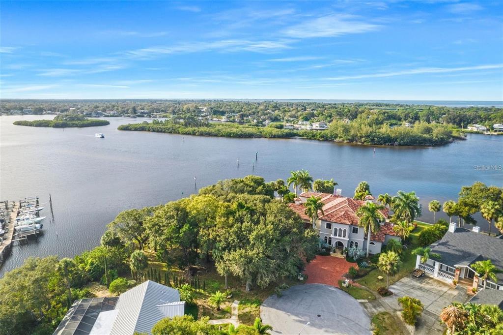 An aerial view shows a waterfront home with a red tile roof surrounded by trees — 1600 MEYERS COVE DRIVE, TARPON SPRINGS, FL