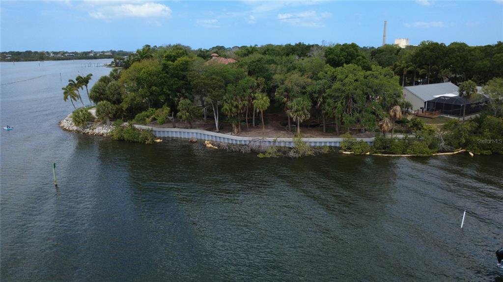 An aerial view shows a waterfront property with a seawall, dense trees, and a house — 1600 MEYERS COVE DRIVE, TARPON SPRINGS, FL