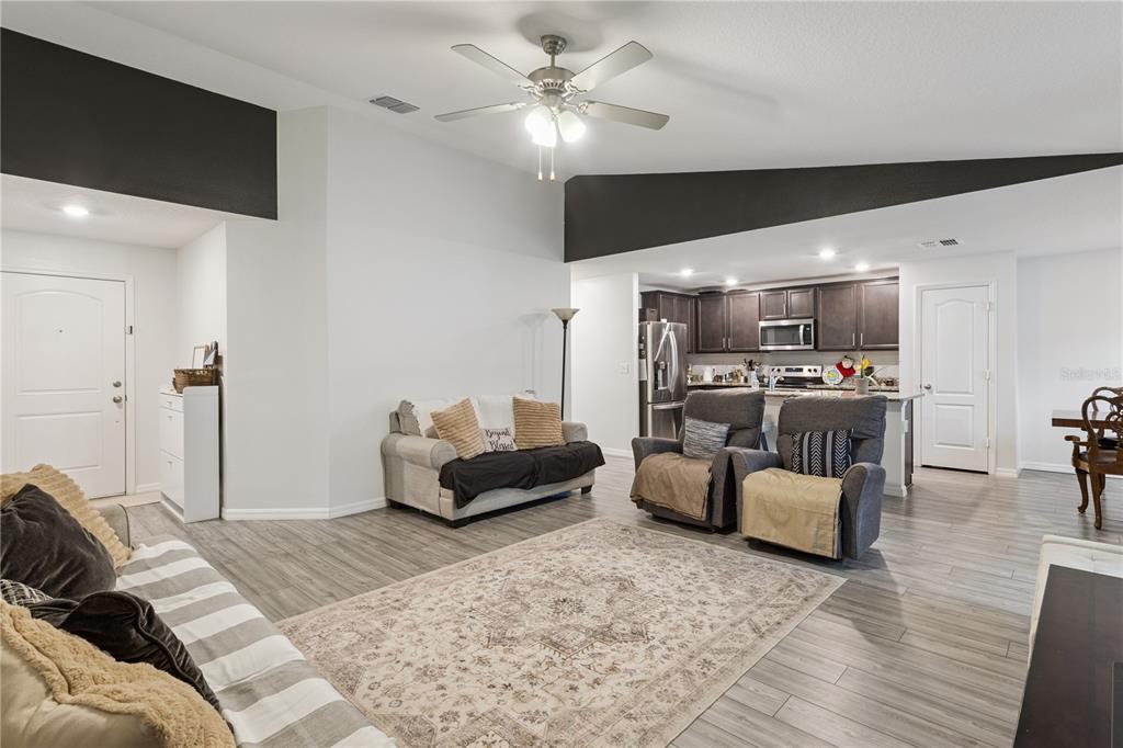 A living room with light wood-look flooring, a ceiling fan, and an open-concept kitchen — 1063 LAKE ARBOR COURT, TAVARES, FL