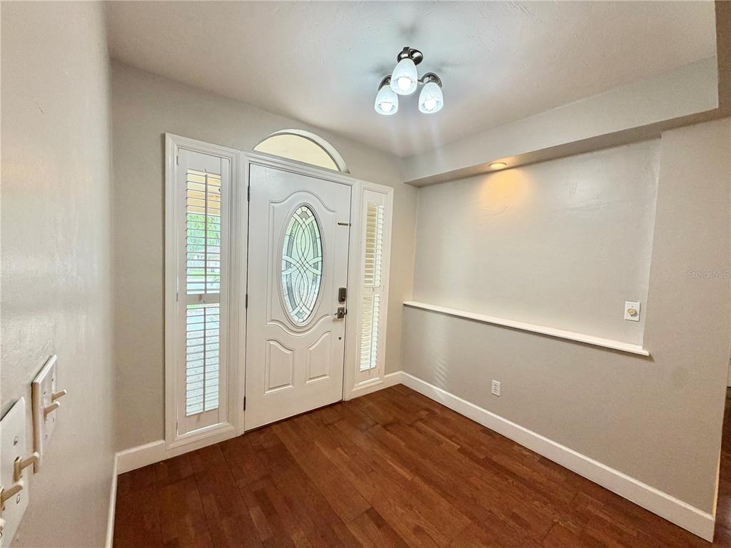 An entryway features a white front door with sidelights, hardwood flooring, and a recessed shelf — 11512 NW 13TH LANE, GAINESVILLE, FL