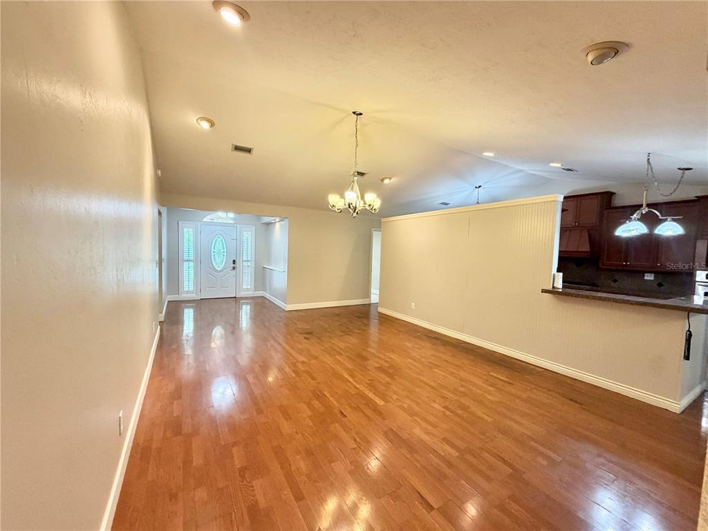 An open-concept living area features hardwood floors, a chandelier, and a kitchen with dark cabinets — 11512 NW 13TH LANE, GAINESVILLE, FL